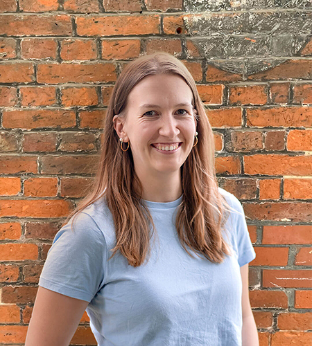 Anika Sprakel lächelnd vor Backsteinmauer