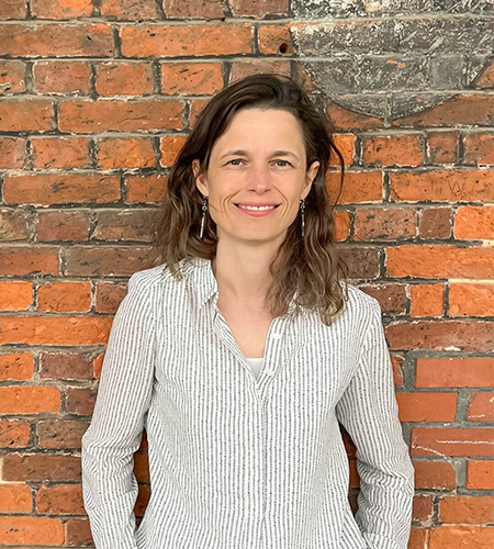 Dr Christine Prauschke smiling in front of a brick wall