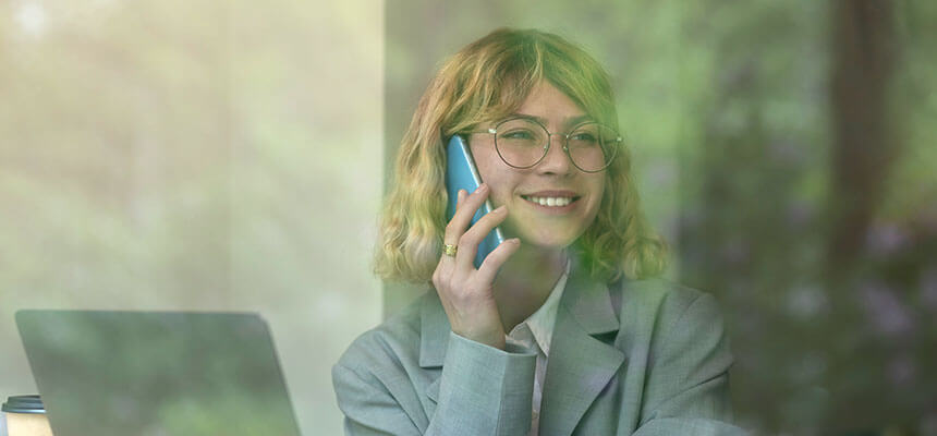 Frau am Telefon vor Laptop als Symbol für effiziente Betreuung, persönlichen Service und digitale Unterstützung im ESG-Management