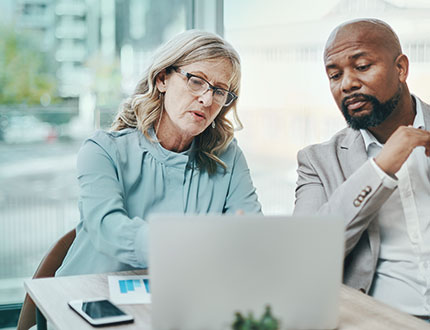 CSRD DNK GRI ZNU CSRD-light, ältere Frau und Mann vor Laptop im Büro