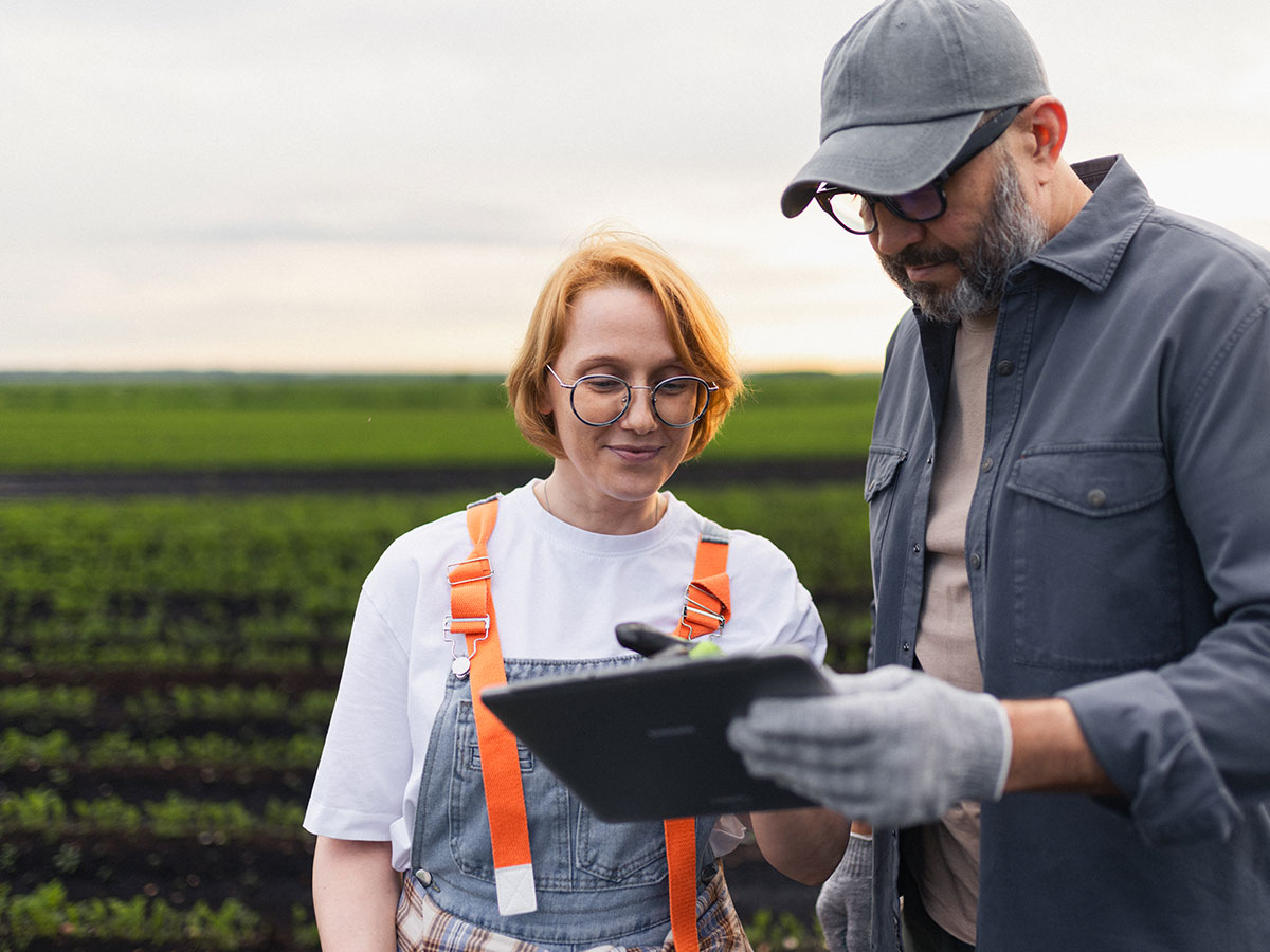 Frau und Mann in Arbeitskleidung vor einem Feld