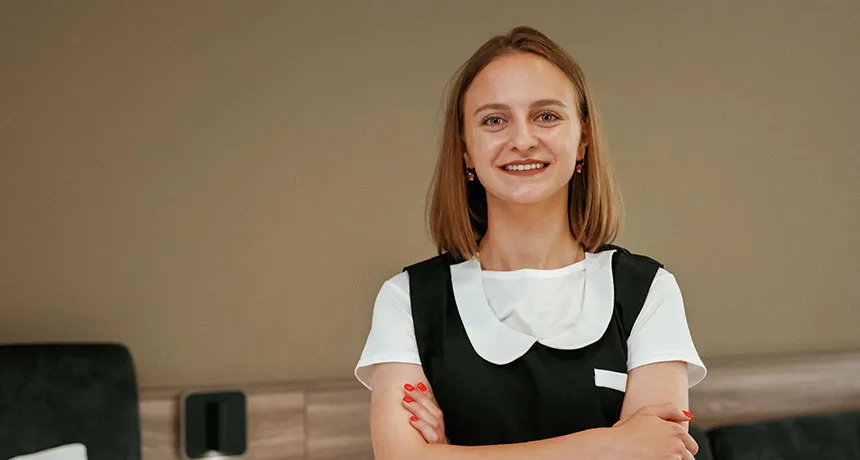 ESG und ISO Branchenlösung Hotellerie, Mehrwert starke Arbeitgebermarke, Hotelangestellte in Hotelzimmer lächelt in die Kamera