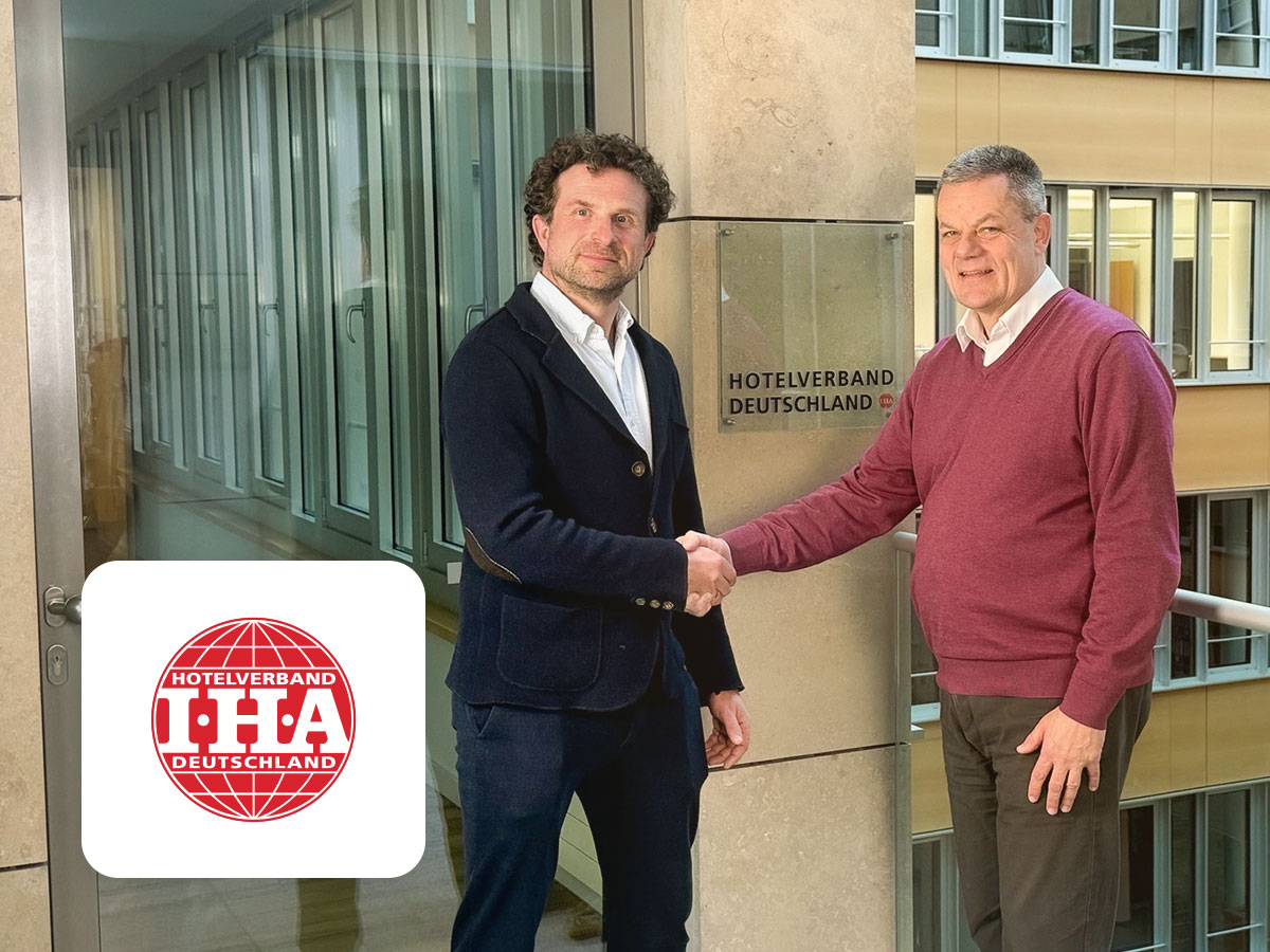 Interview IHA Hotelverband Deutschland Titelbild, IHA Logo, Christian Hechler-Wien und Markus Luthe Händeschütteln