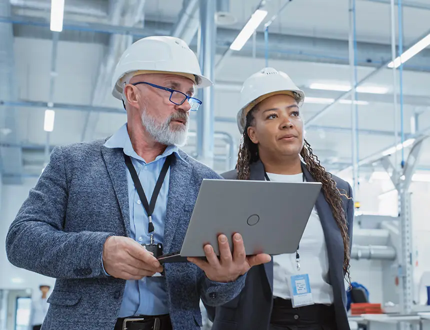 Lösungen - ISO Strategie, ISO Management, ISO Zertifizierung, Mann und Frau mit Laptop und Ausweis in Fabrikhalle