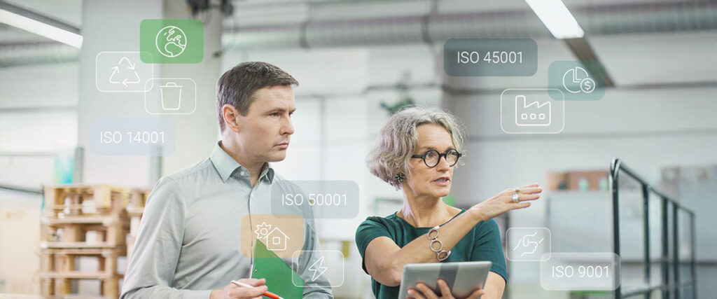 Von ISO zu ESG - Mann und ältere Frau, die sich unterhalten, Mappe und Tablet in den Händen