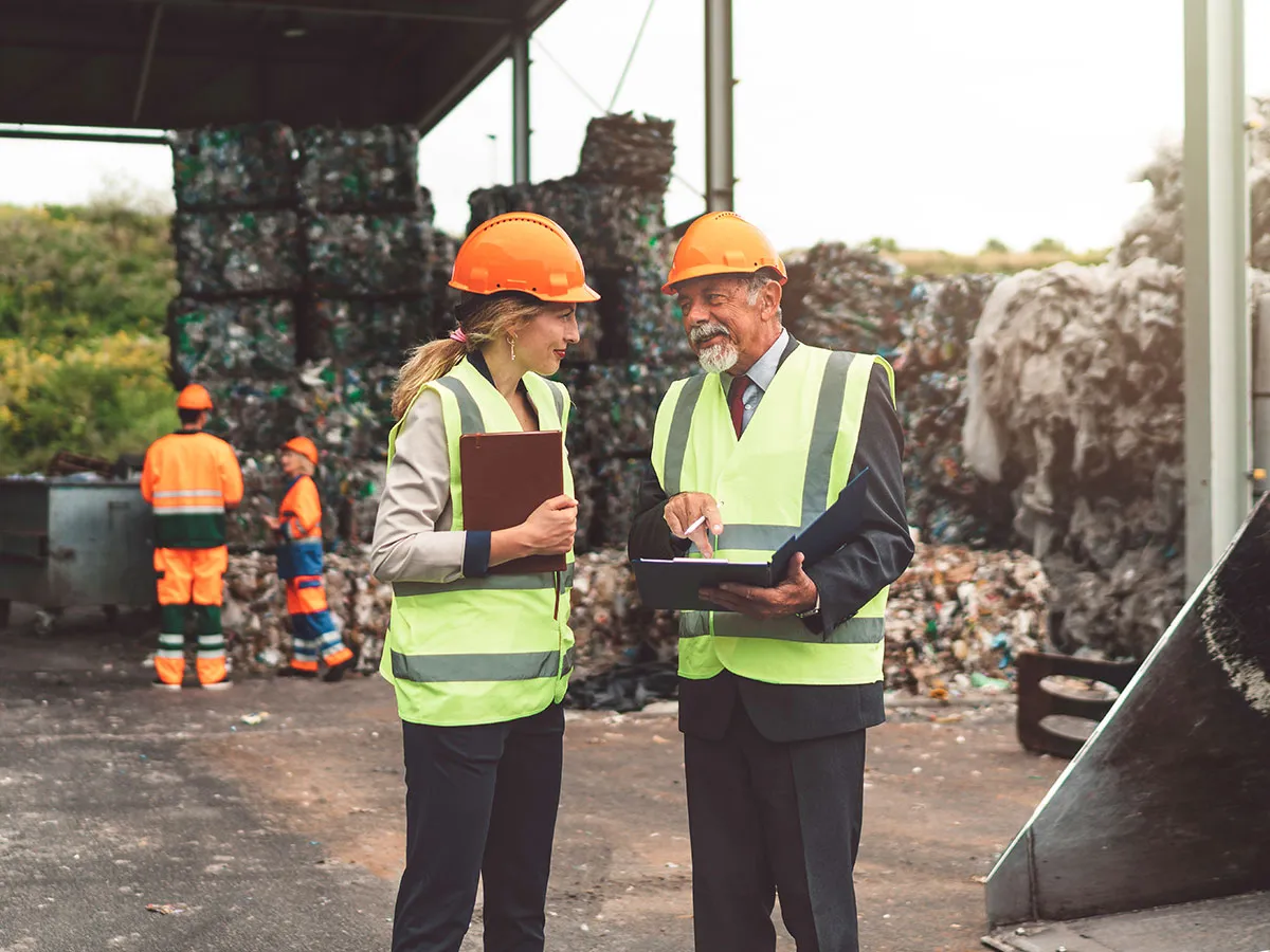 Zwei Fachkräfte im Recyclingbetrieb sprechen über Verpackungen und Abfallmanagement im Kontext der PPWR-Verordnung